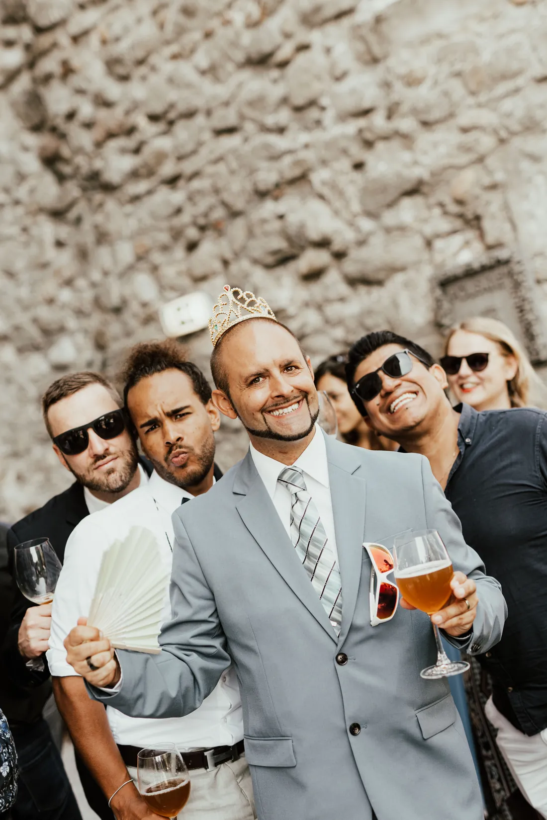 Hochzeitsgäste mit Sonnenbrillen und Bier stossen lachend an