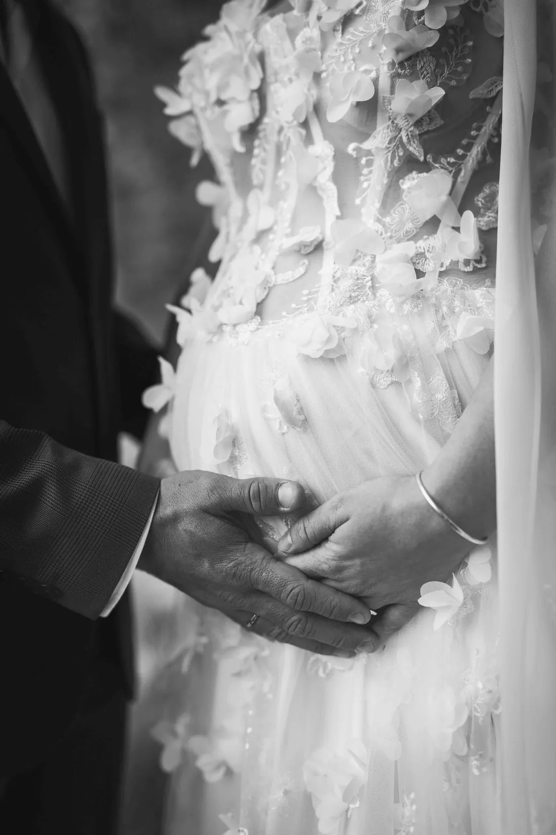 Hände auf dem Spitzenkleid der Braut in Schwarzweiss