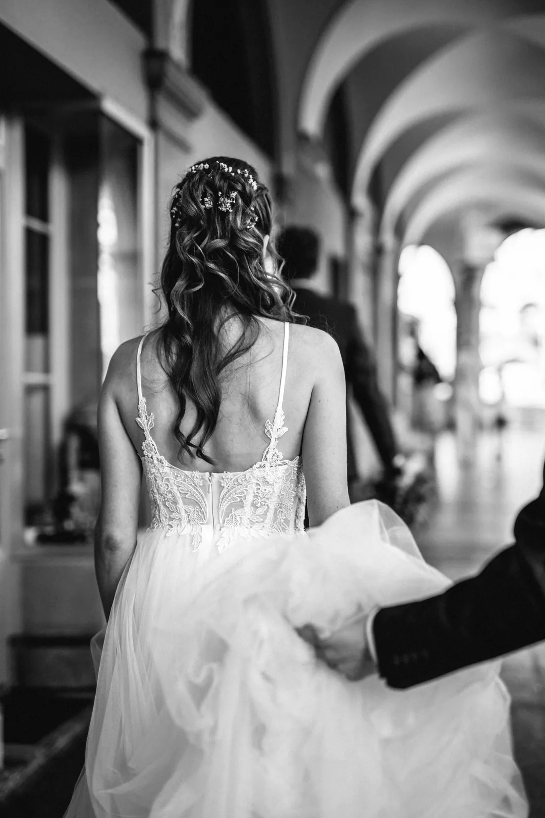 Braut von hinten in einem Säulengang, das Kleid wird getragen