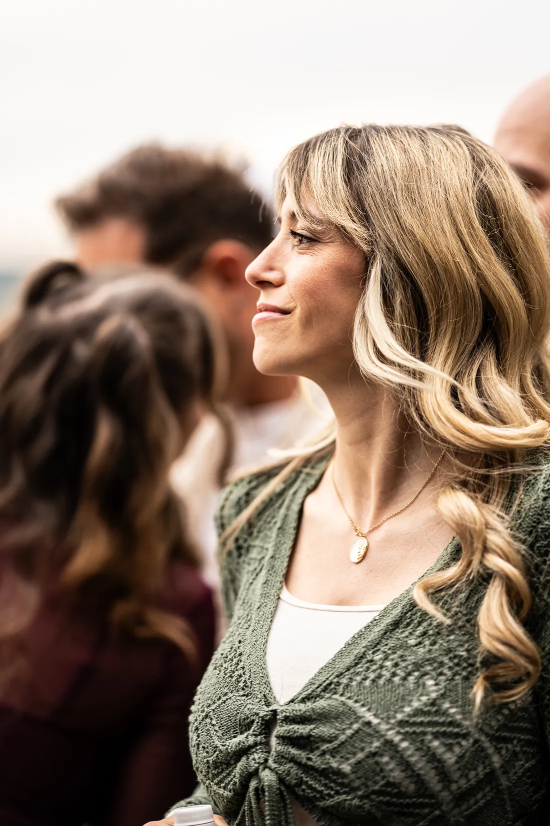Hochzeitsgast mit blondem Haar schaut lächelnd zur Seite