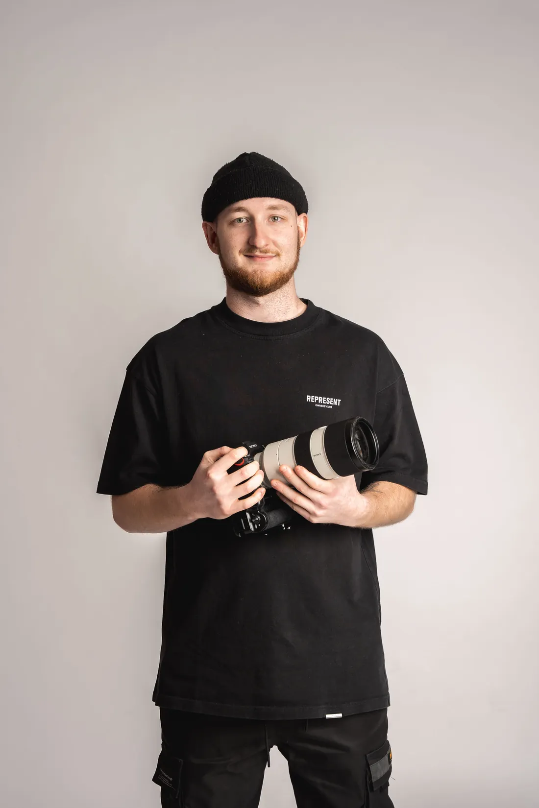 Florin Schmid mit Kamera vor hellem Hintergrund