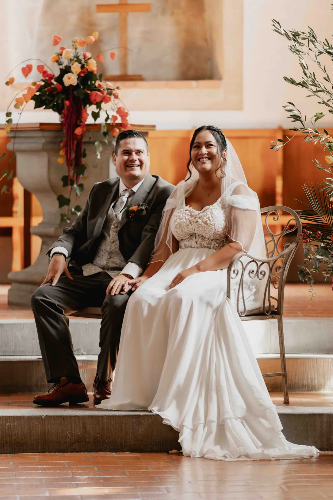 Brautpaar sitzt lachend vor dem Altar