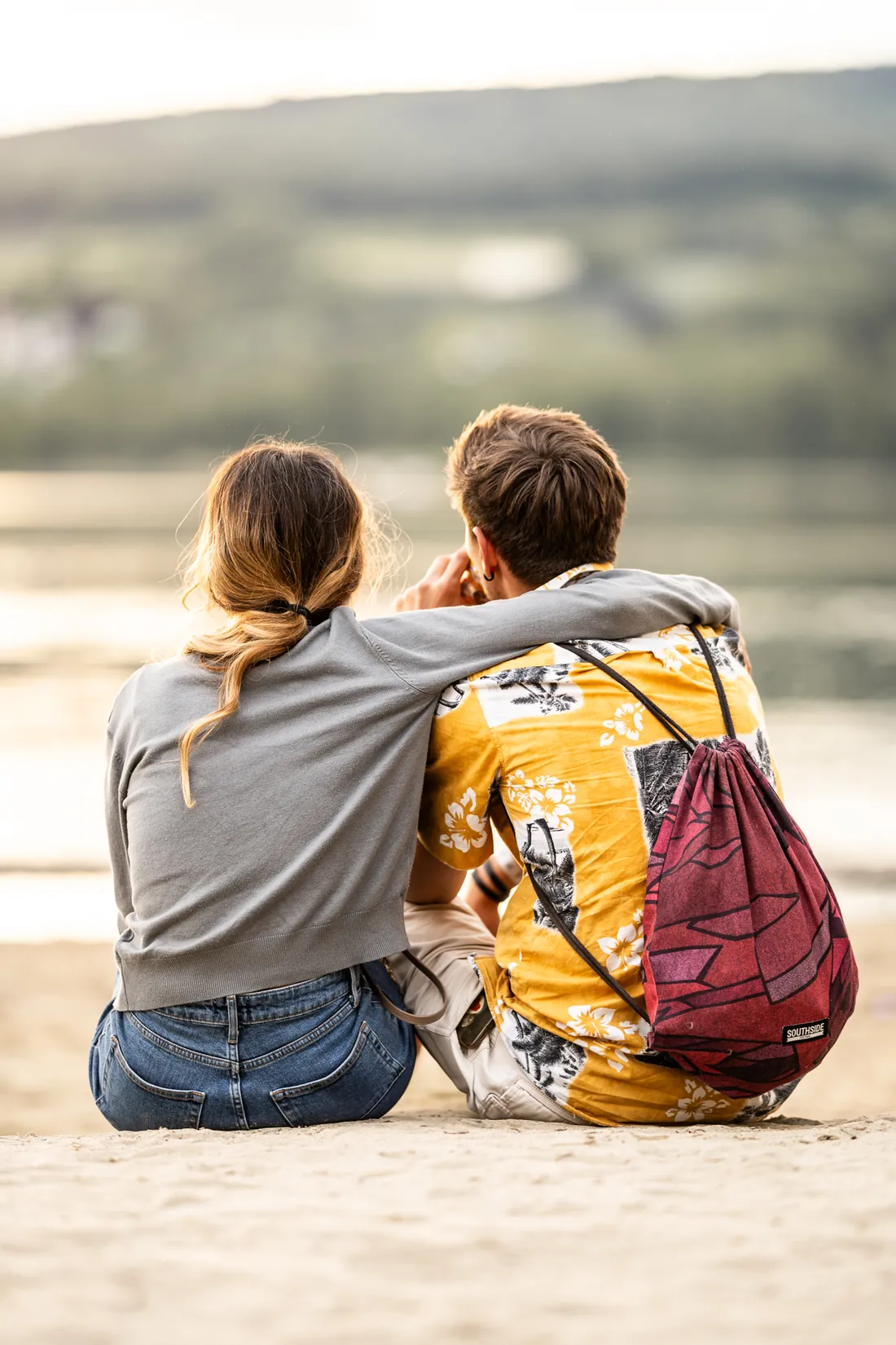 Paar sitzt von hinten gesehen am Seeufer