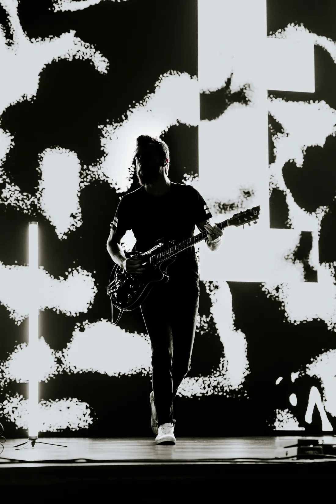 Gitarrist als Silhouette vor einer gemusterten Leinwand