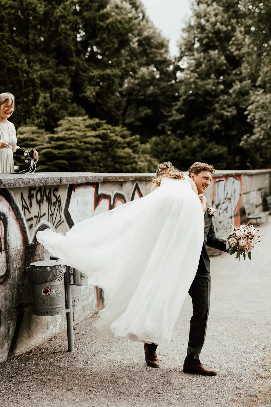 Bräutigam wirbelt die Braut vor einer Brücke mit Graffiti herum