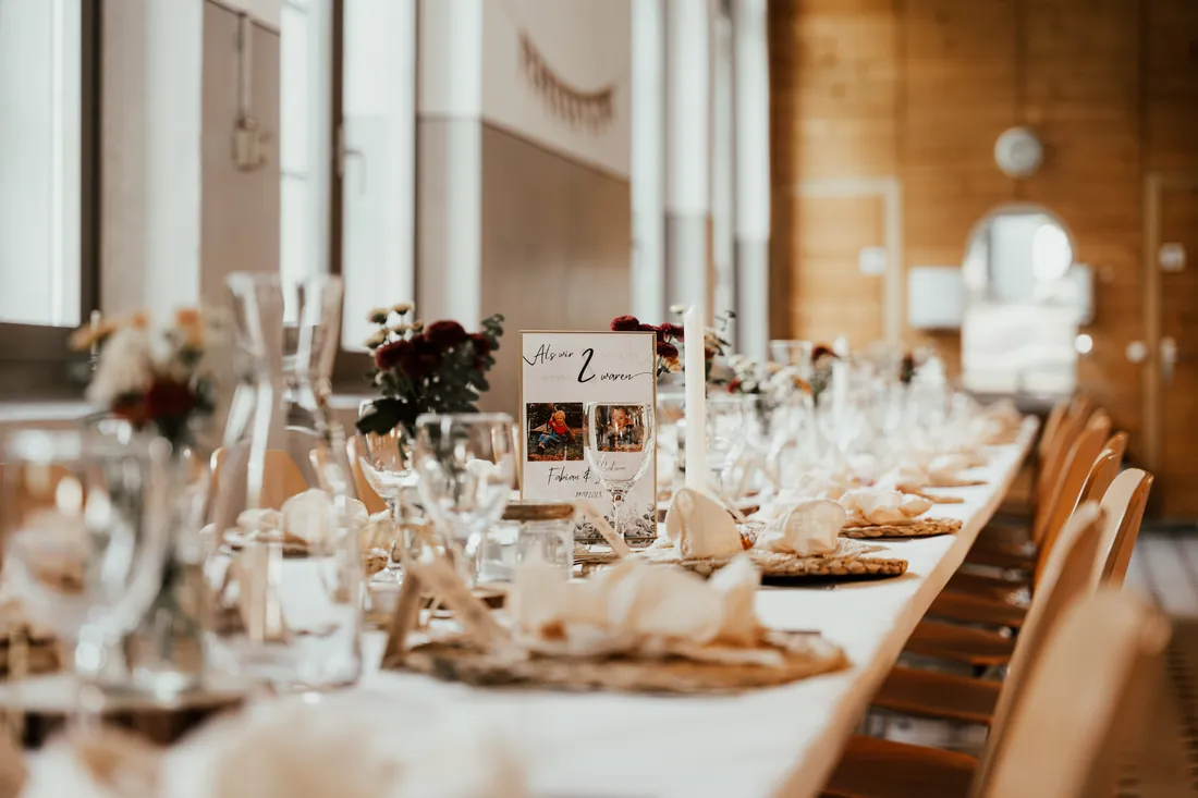 Lange gedeckte Hochzeitstafel in einem hellen Saal