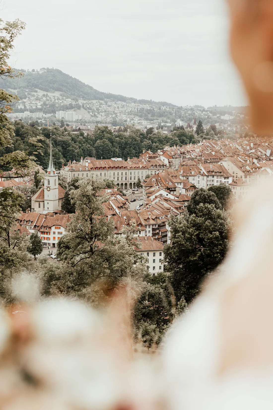 Blick über die Dächer einer Altstadt, das Kleid unscharf im Vordergrund
