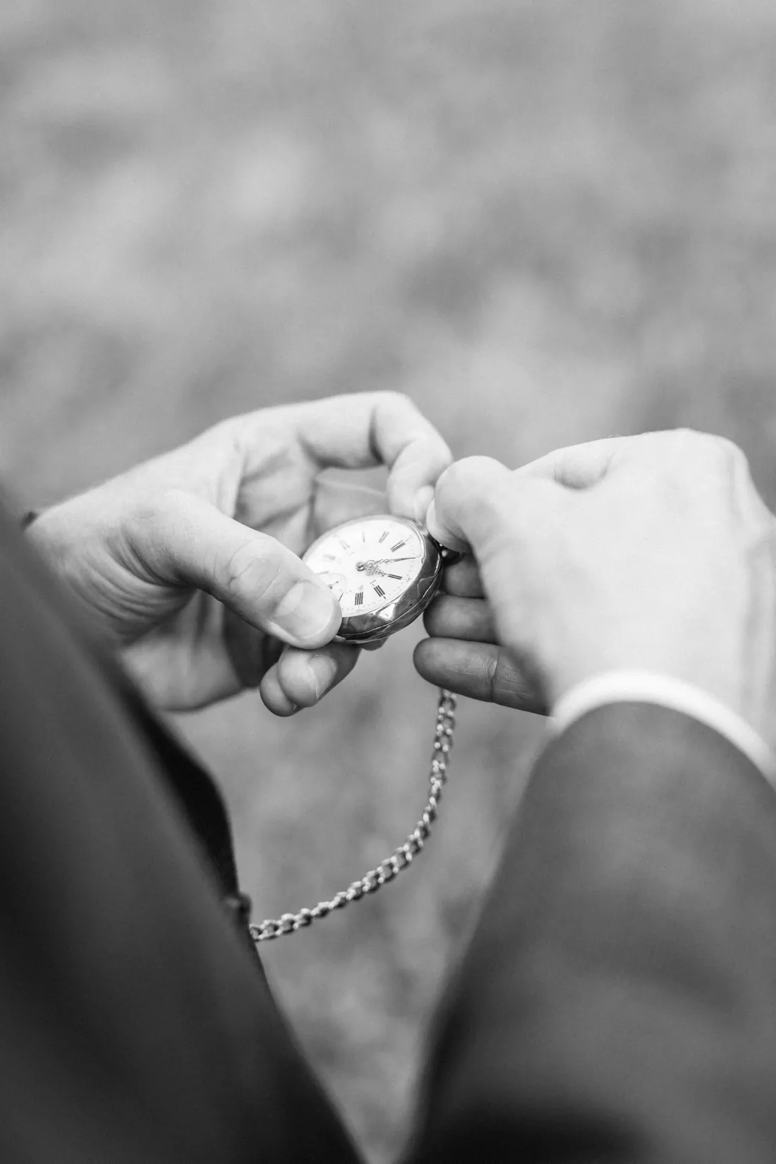 Hände halten eine Taschenuhr an einer Kette, Schwarzweiss