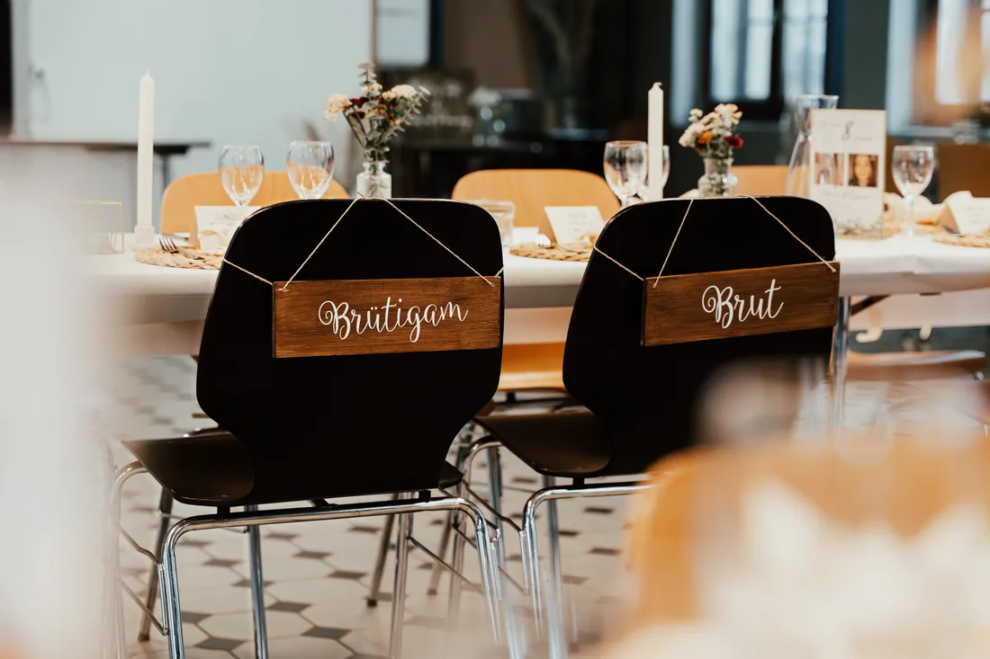 Stühle mit Holzschildern «Bräutigam» und «Braut» am Hochzeitstisch