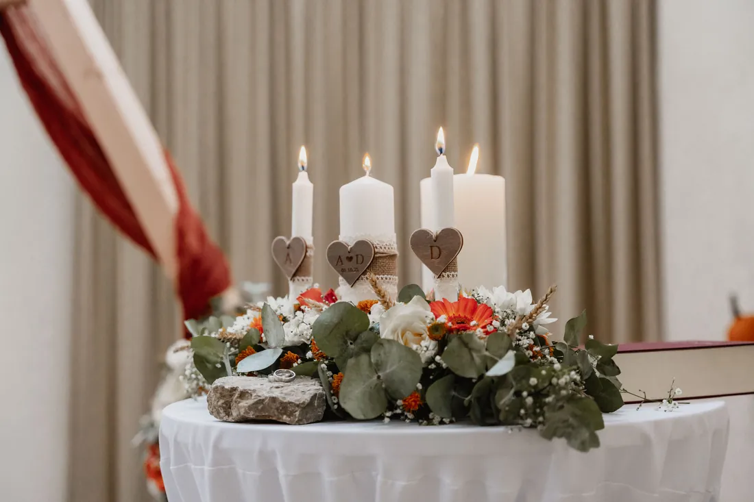 Tischdekoration mit Kerzen, Holzherzen und Blumen