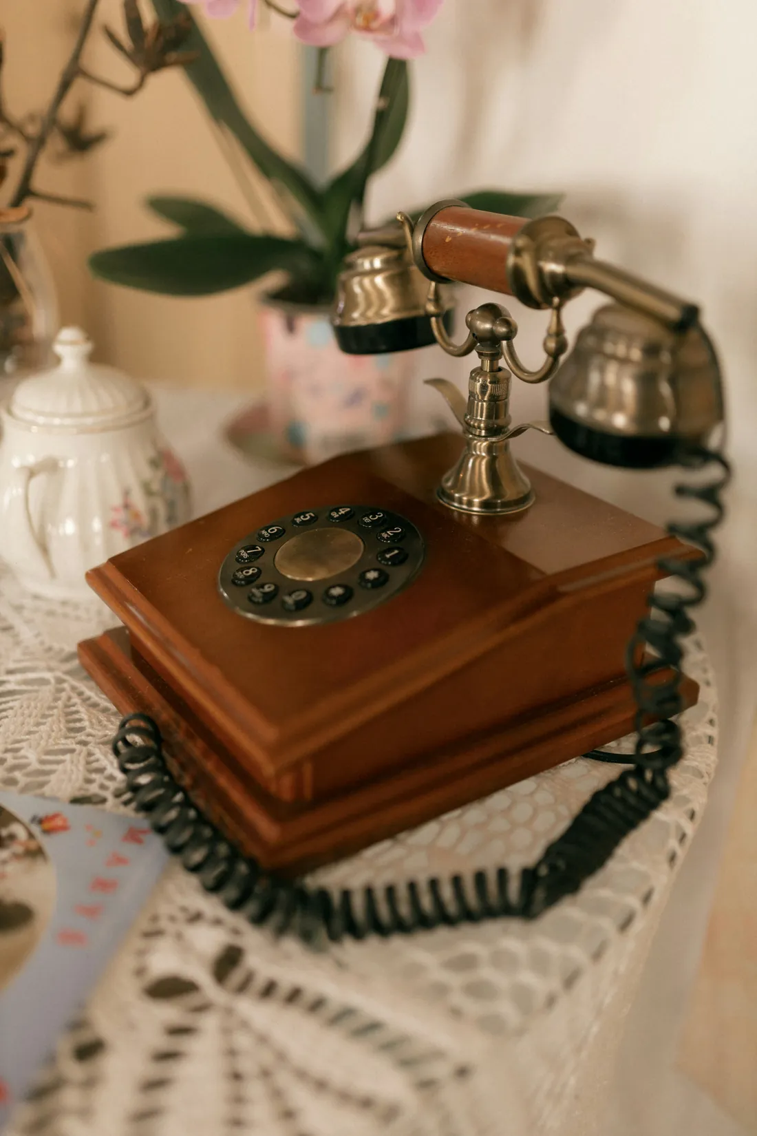 Antikes Telefon mit Wählscheibe auf einer Spitzendecke
